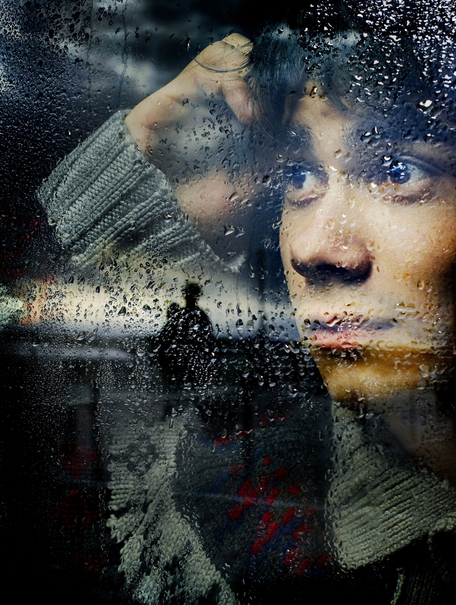 Portett av musiker Alexander Rybak bak et vindu med regndråper. 

