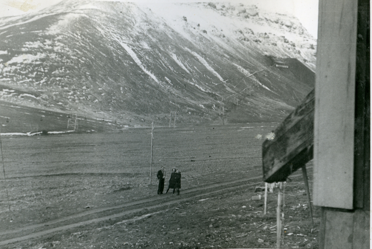En mann og to kvinner på veien i Longyearbyen 1940/41. Gruve 2b i bakgrunnen. Bildet er tatt av Jens A. Bay, som arbeidet i gruva vinteren 1940/41.