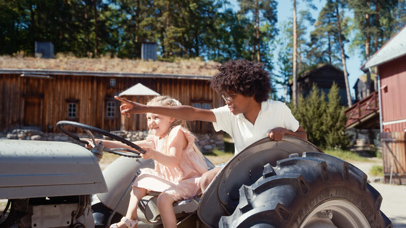 To barn sitter på traktoren Gråtass