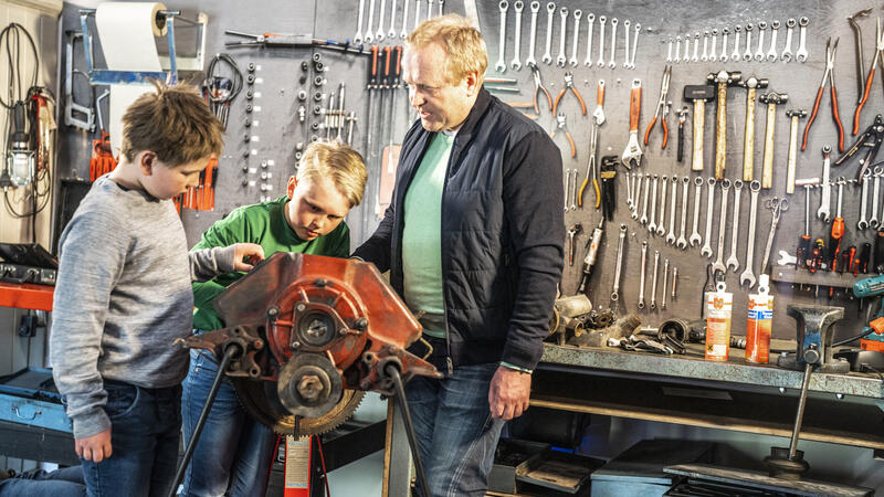 Bildet viser tre besøkende åp museet som studerer en motor.
