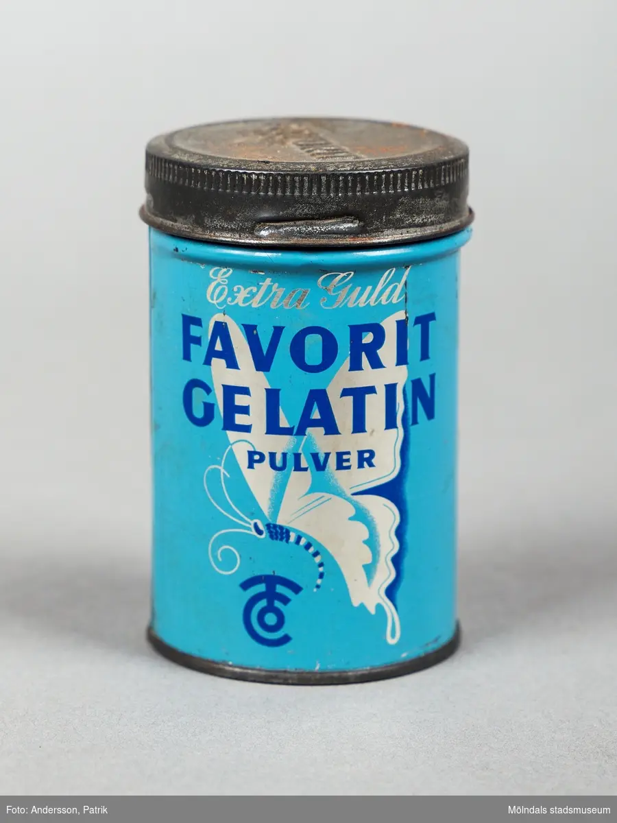 En mellanblå plåtburk med ett silverfärgat lock som innehållit gelatin pulver. Det står Extra Guld med skrivstil längst upp på framsidan. Därunder står det Favorit Gelatin med versaler med blå text. 
En silverfärgad fjäril pryder burken under bokstäverna.
Text på baksidan:
Favorit gelatin Pulver är framställt av råvaror av högsta kvalitet och är smak och luktfritt.