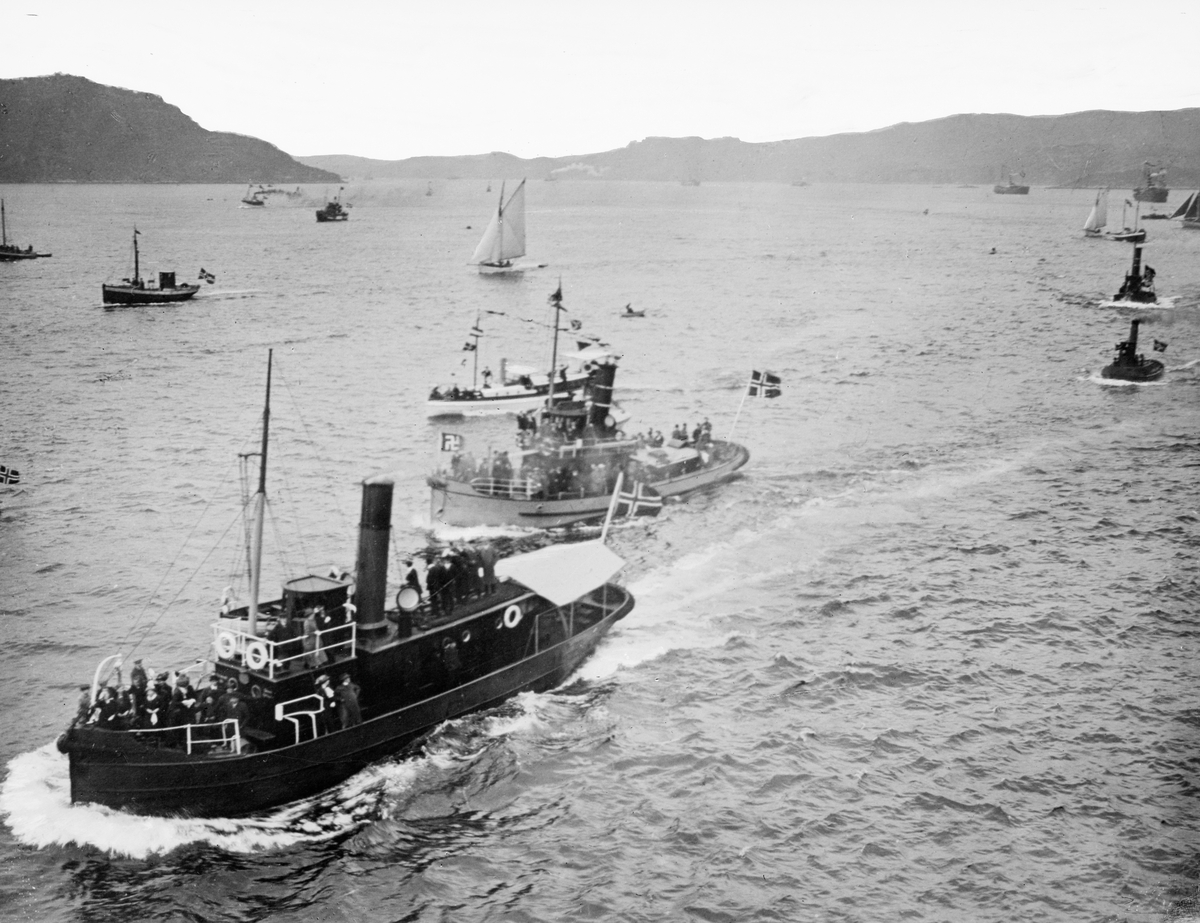 Fjordparti ved Bergen med flåte av ulike båter som markerer kongebesøket. Bildet er del av en serie tatt i forbindelse med passasjerskipet "Kristianiafjords" første seilas mellom Oslo og Bergen 4.-7. juli 1913. 