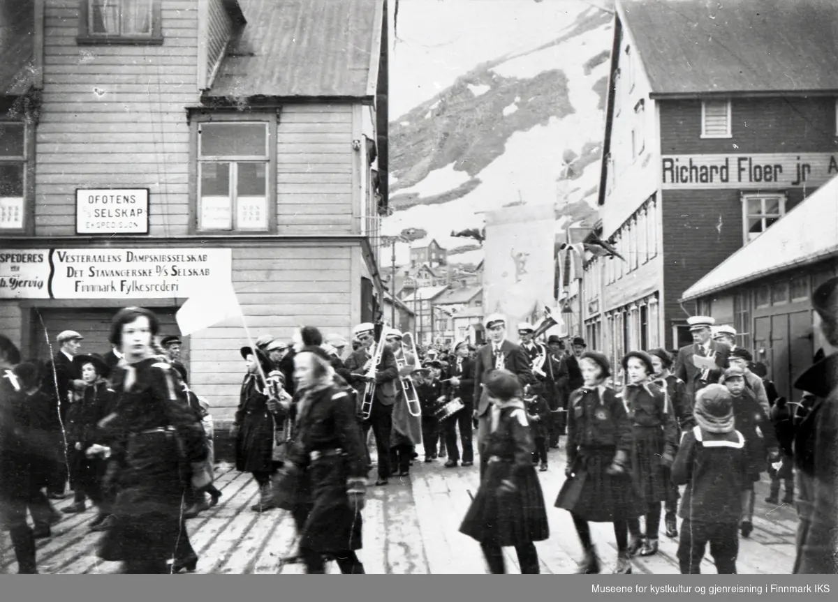 Honningsvåg. 17. mai-tog på Holmen. Speidertroppen passerer Dampskipsekspedisjonen og Richard Floers brygge.