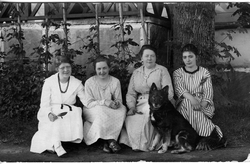 Fire kvinner samlet ute i en hage. Elever og lærer på husmor
