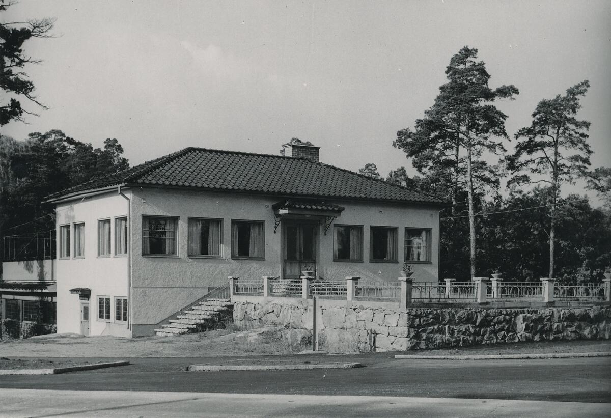 Skurustugan med adress Värmdövägen 399 byggdes år 1947 och hade därefter olika ägare tills Nacka kommun tog över fastigheten år 1964. År 1999 köptes fastigheten av Skuru IK som idag använder det som klubblokal. Foto ca 1960.