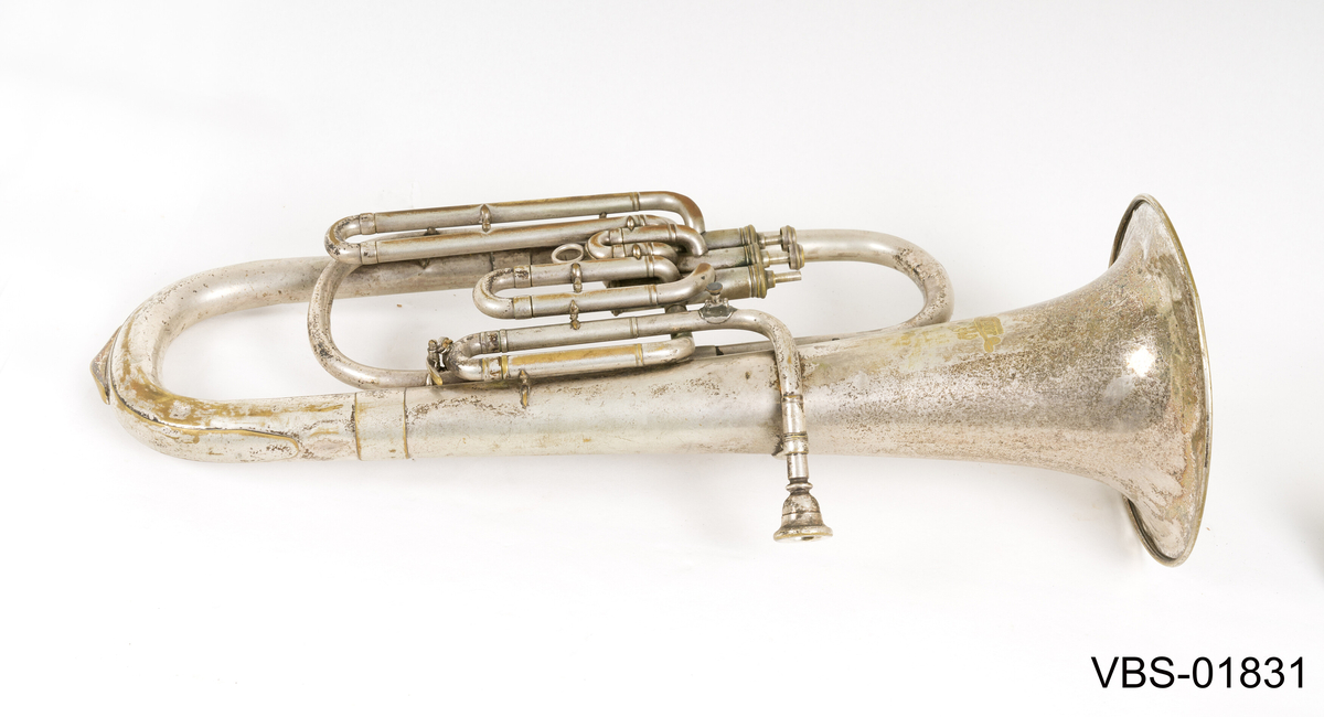 Blåseinstrument i forsølvning messing med tre ventiler. 
Tubaen har et etui tilpasset formen, med et håndtak. Instrument etuiet er foret på innsiden med et mørkeblått ullbelegg, og dekket utenpå med svart kunstlær.