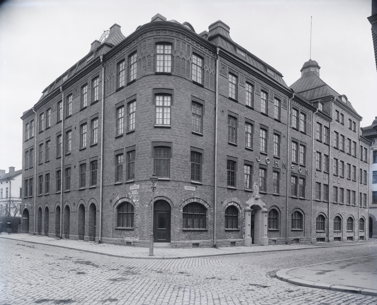 Johnson & Hill, fyra vånings fabriksbyggnad i rött tegel, ett torn, tornhuvar. Fastigheten ligger vid Klostergatan - Fredsgatan -Gamla gatan.
Pappersgrossist, kuvertfabrik, boktryckeri, papperspåsfabrik, litografisk anstalt.