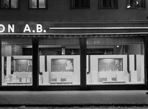 Fasad med skyltfönster hos Ekelöf & Svensson AB.
1872 etablerade fröknarna Hilda Ekelöf och Carolina Svensson en detaljaffär i manufaktur. Vacklande hälsa gjorde att firman 1897  överläts till Wilh. Welin som skapade nya avdelningar, till exempel flaggtillverkningen (1900) och en syatelje för klänningar (1905) samt en modeaffär (1914) där bland annat Josefin Baker gick modell.  Sommaren 1999 lades verksamheten ner på grund av olönsamhet.
Källa: Nyblom-Svanqvist, Näringsliv i Värmland, 1945 och Värmlands Folkblad.