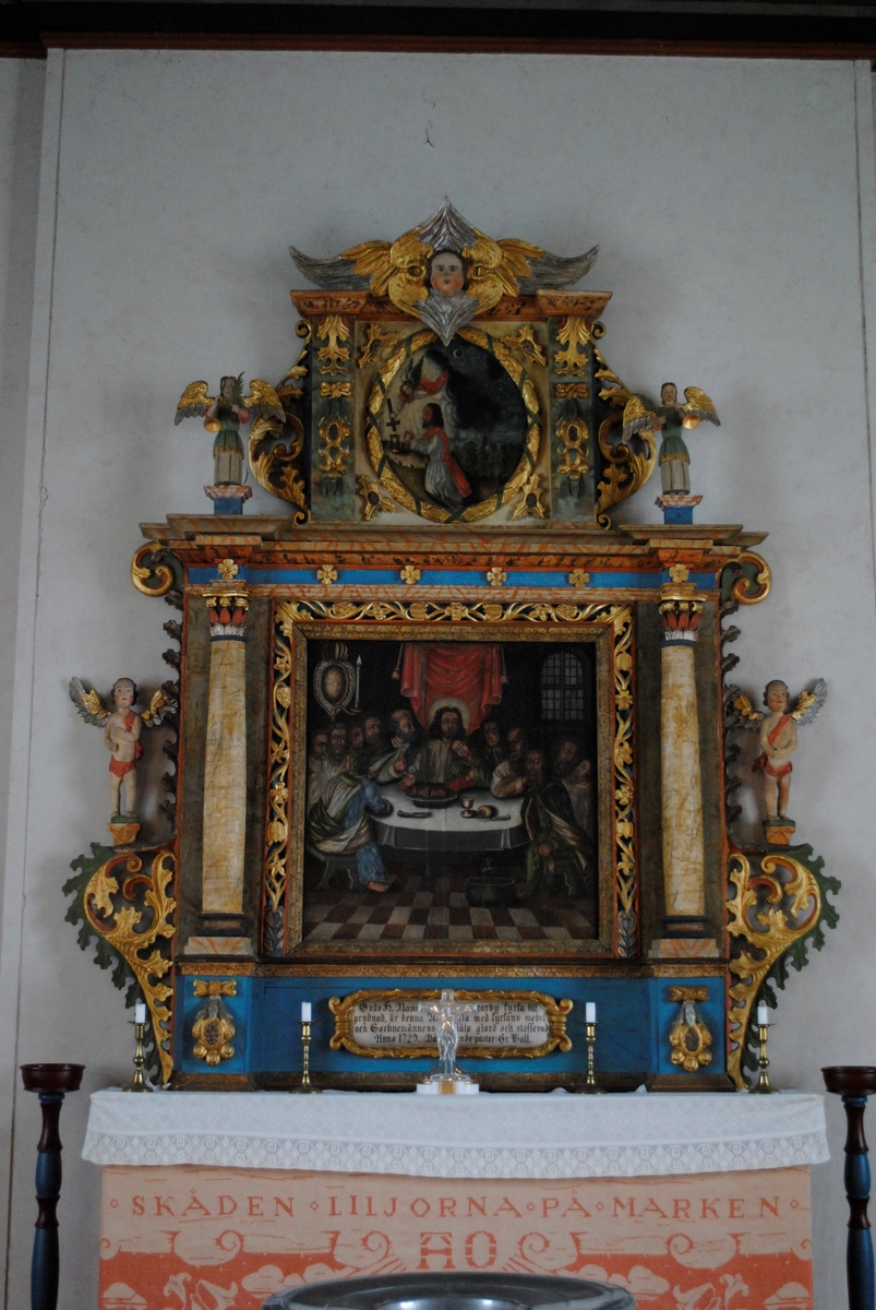 Interiör i Laxarby kyrka. I dopkapellet i norra korsarmen finns kyrkans äldre altaruppsats från 1729 som skildrar nattvardens instiftande, samt en dopfunt av täljsten är från 1200-talet.