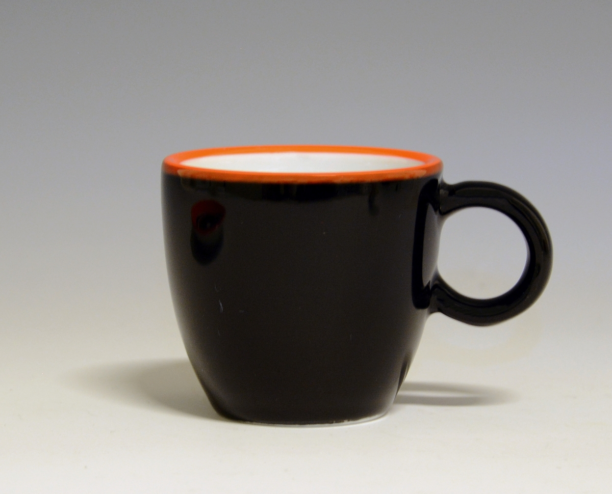 Espressokopp av porselen, med med rund hank. Sort med rød topprand, hvit inni.

Modell: Barista, forgitt av Poul Jensen.
Dekor: Gama

