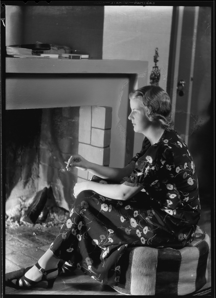 Kvinne sitter ved peisen med en sigarett i hånden 