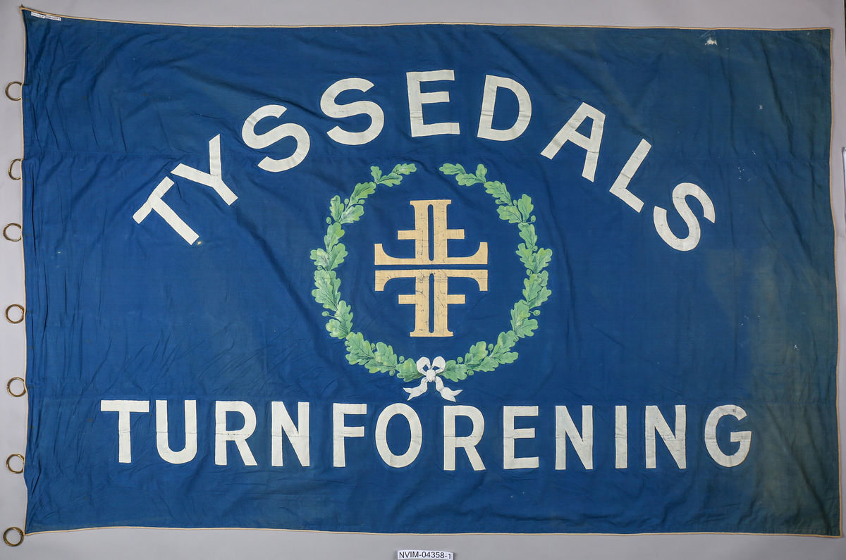 Motiver er sett saman av to eikegreiner bundne saman med ei sløyfe og Turnforbundet sitt symbol/logo, 4 F-ar, i midten.