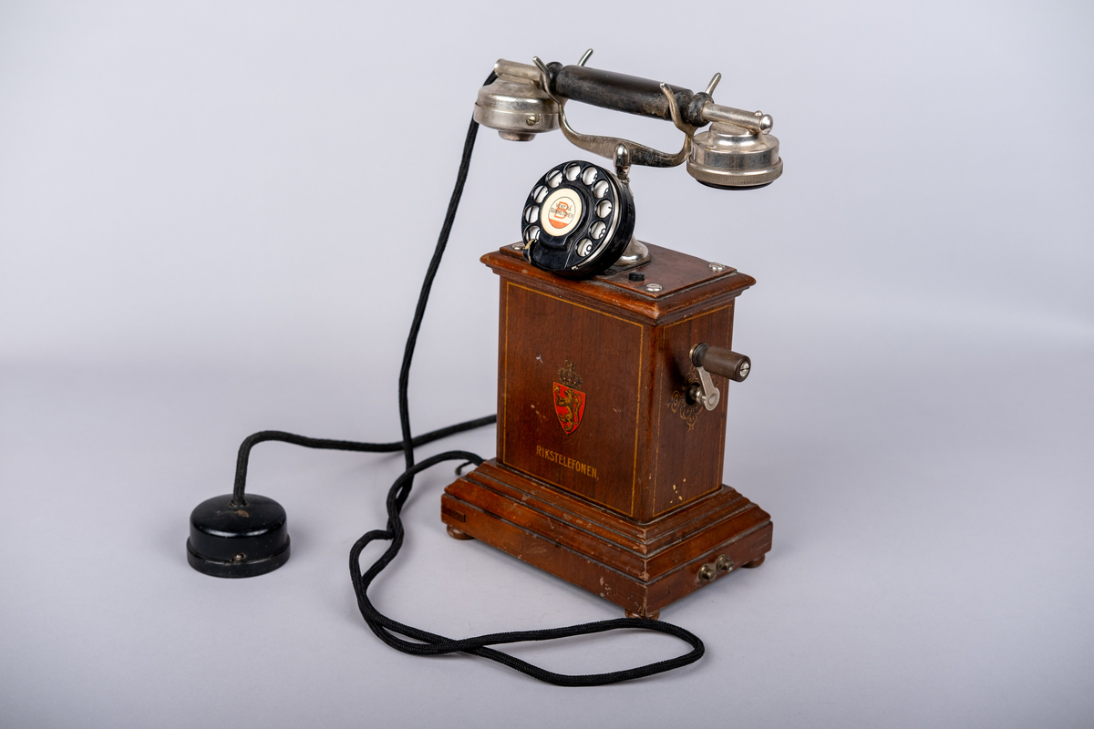 Rikstelefonenns bordtelefon fra 1918.
Telefonen består av telefonrør, telefon med tallskive, kabel og ledning. 
Tallskivet har tall 0-9.
Sveiv på høyre siden.  
På front siden riksvåpen med løven og kkronen, under det "RIKSTELEFON"-
