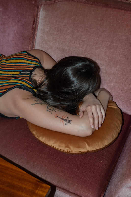 Bilde av en person som ligger med hodet på et par puter. Høyre overarm har tatoveringer.