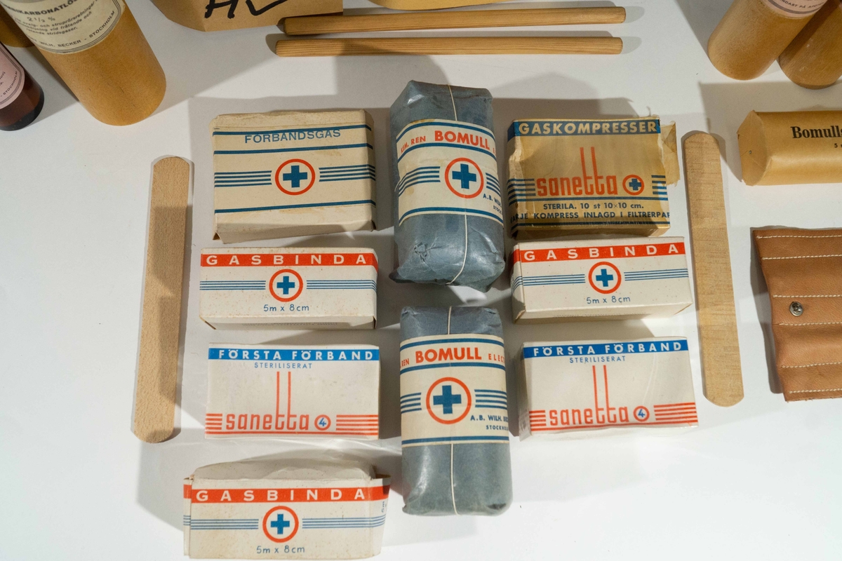 Förbandsväska med blått kors. Etiketten ”FKP HV” avser sannolikt hemvärnet i Falköping.
Väskan innehåller:
1 häfte Luftskydd – korta anvisningar för envar (Luftskyddsinspektionen, allmänna anvisningar Nr. 3).
3 paket fetvadd
3 paket gasbinda 5 m x 8 cm
1 paket förbandsgas
10 st gaskompresser 10 x 10 cm
2 paket kemiskt ren bomull
2 paket bomullstygbinda 5 m x 10 cm
2 första förband
1 fodral i läder med sax och pincett
2 tungspatlar
2 blyertspennor
Flaskor i träfodral:
Saneringssprit
Garvsyrepuder
Natriumbikarbonatlösning 2½%
Luktlösning
Jodsprit 5%
Borsyresalva
Kloraminlösning