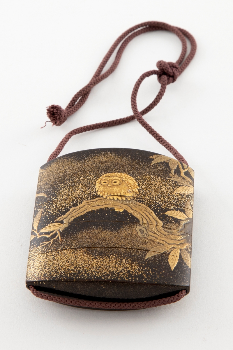 Fem-delt inro med ovalt snitt. Gjennomgående løpegang for snor. Dekor i relieff og gull-lakk (taka-makiye) på sort bunn med gullstøv (nashi-ju). Motivet viser en ugle sittende på en kastanjegren.