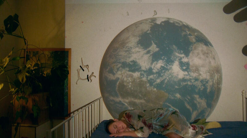 Bilde av en kvinne som ligger og sover med en jordklode over seg.