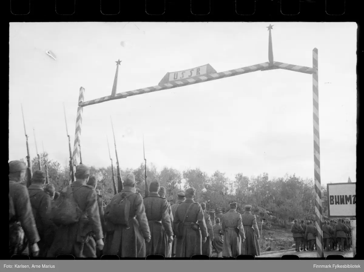Russiske soldater på grensa i Sør-Varanger ved grensebom i Storskog. Soldatene bærer på våpen. I følge notat tilhørende bildene var bildene tatt av en russisk fotograf 

I foto kan man se en grensebom med teksten USSR samt et skilt til høyre med kyrilliske bosktaver 
