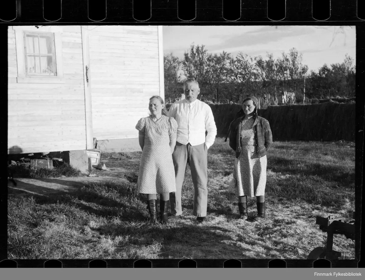 Foto av familie utenfor hus. Muligens familien Saba, usikker identifisering. 

Kvinnen til høyre har på seg et samisk hodeplagg 

Foto antagelig tatt på slutten av 1940-tallet, tidlig 1950-tallet 