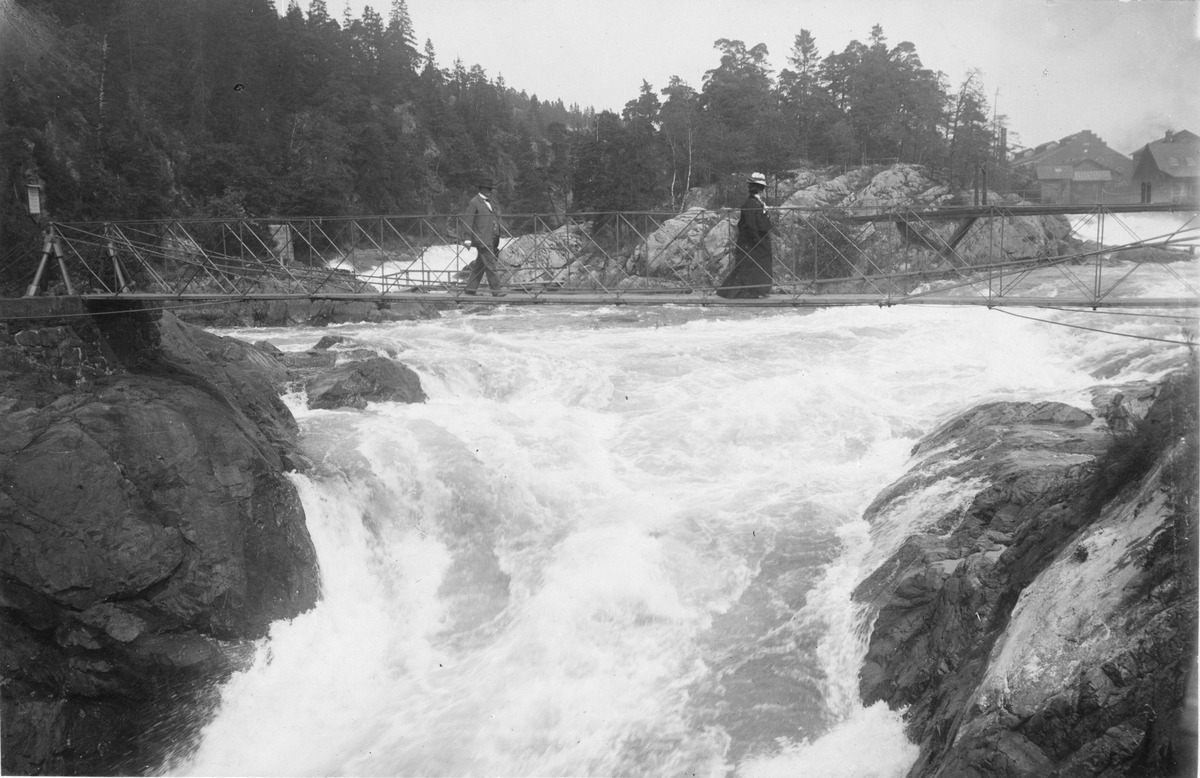 Kvinna och man på bron över Toppöfallet, Trollhättan. Omkring 1905.