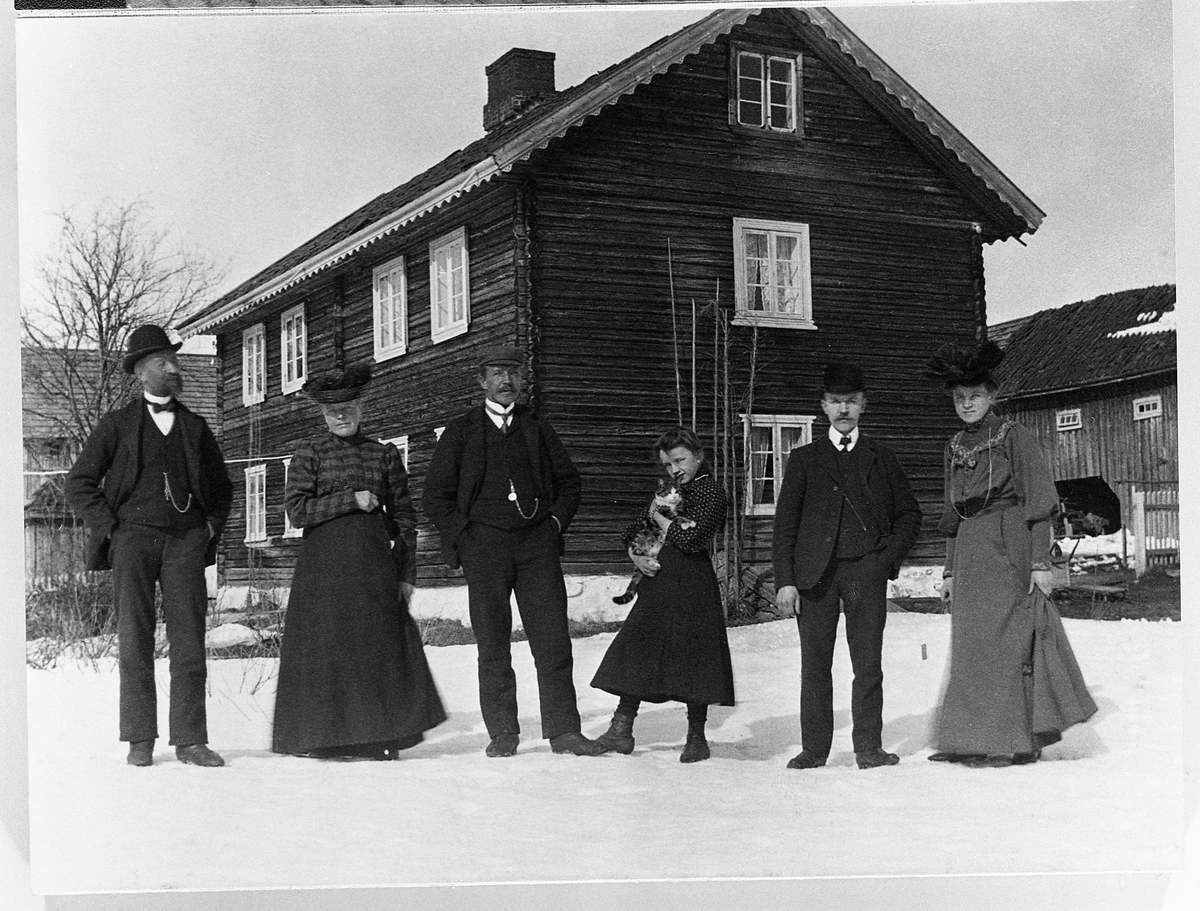 Seks personer avbildet foran et tømret våningshus i 2,5 etasjer på Eina i Vestre Toten 19/4-1908. Personene er: Johannes, Andrine, Bernhard, Anna, Mathias og Marie, alle med etternavn Skinderviken.