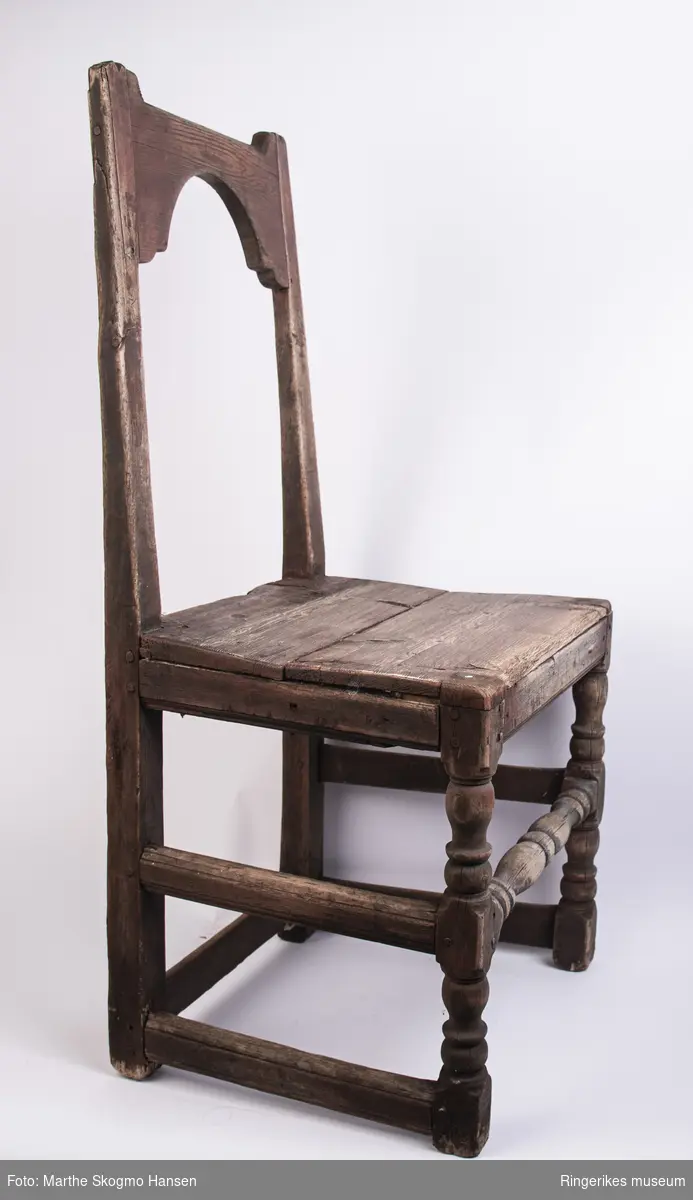 Trestol med åpent ryggbrett, toppstykket er halvsirkelformat i nederkant og rett i overkant, og dreide forbein. Antakelig fra 1700-tallet.