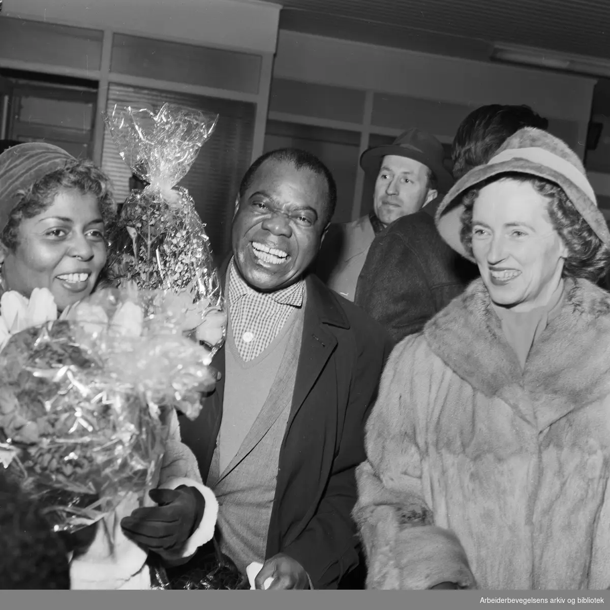 Louis Armstrong ankommer Oslo via Fornebu flyplass 2 februar 1959. (hans kone Lucille Wilson til venstre). Til venstre, ukjent.