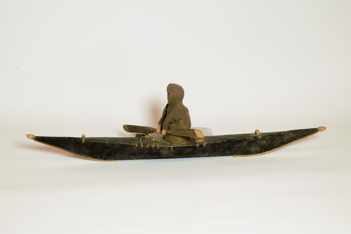 Sjømannsouvenir. Modell av kajakk med eskimo som padler. Kjøpt på Grønland av sjømann tilhørende Gabrielsens Rederi, Farsund