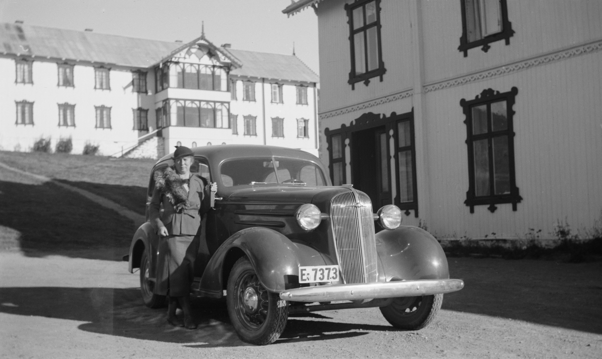 Dame som står ved en Chevrolet 1936-modell med Fokstugu fjellstue i bakgrunnen