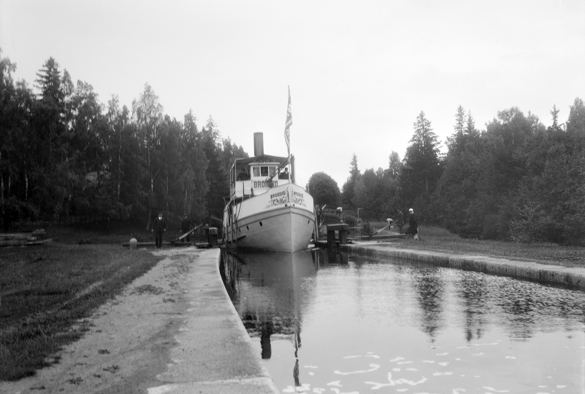 Ångaren Brokind i Hovetorps sluss. Fartyget var byggt vid Bergsunds Mekaniska i Stockholm 1878 och samma år insatt i trafik på Kinda kanal. Bilden kan dateras till tidigast segelsäsongen 1896, från vilket år ångaren ombyggts med bland annat damhytt i aktern och så kallat skvättbord i fören.