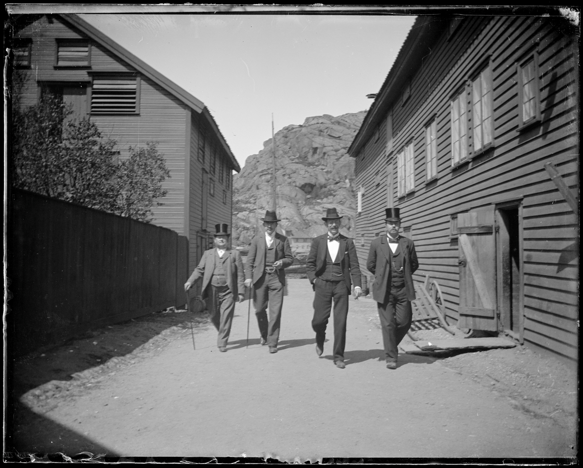 4 menn går gatelangs i Egersund ved O.H. Bøes eiendom