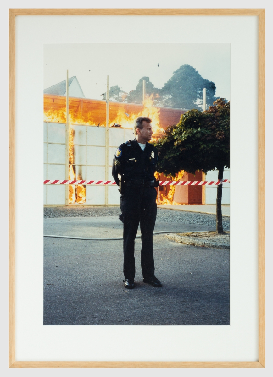 Fotografi av en polis som vaktar en brinnande konsthall.
