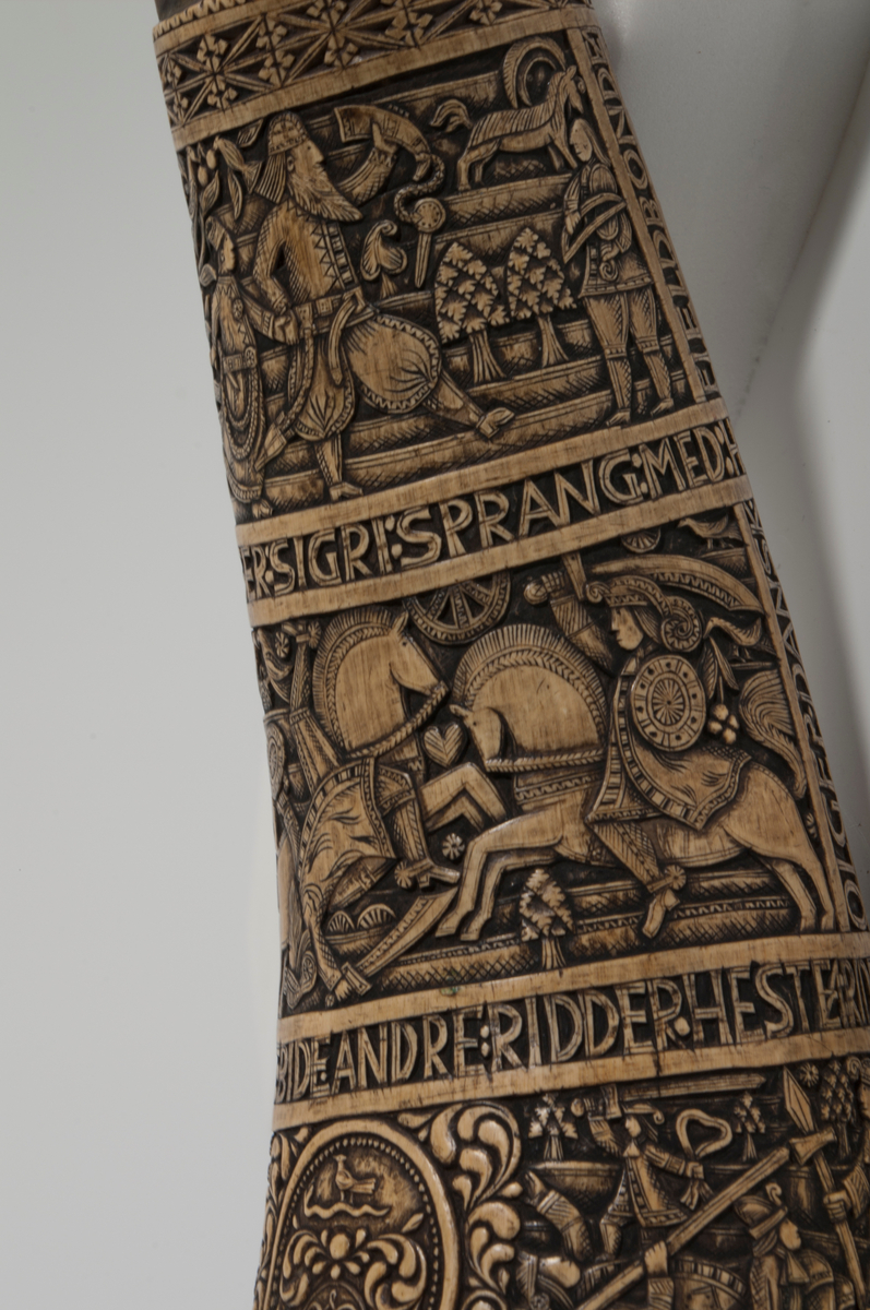 Rikt dekorert horn med skårne dekorasjoner i fem horisontale belter og flere små figurfelt med religiøse motiv. I det første beltet nærmest munningen er det fire figurfelt som viser: 1. Adam og Eva, 2. Jakob og engelen, 3. Daniel og "dragen", 4. Speiderne. Det andre beltet har tre figurfelt som fremstiller ryttere til kamp. I det tredje beltet er det en sirkel som viser Absalon som henger etter håret. På hver sin side av sirkelen vises Samson og løven og David og Goliat. Det fjerde beltet viser ryttere til kamp og det femte beltet nærmest spissen, viser en fjellbonde og en kjøpmann. Mellom figurfeltene er det en rekke innskripsjoner.