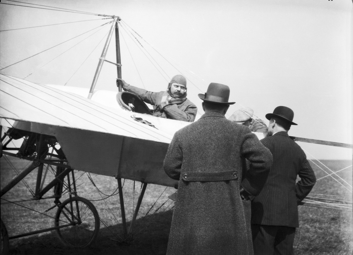 Två flygare i flygplan Bleriox XI. Två män i förgrunden. Vy från sidan ...