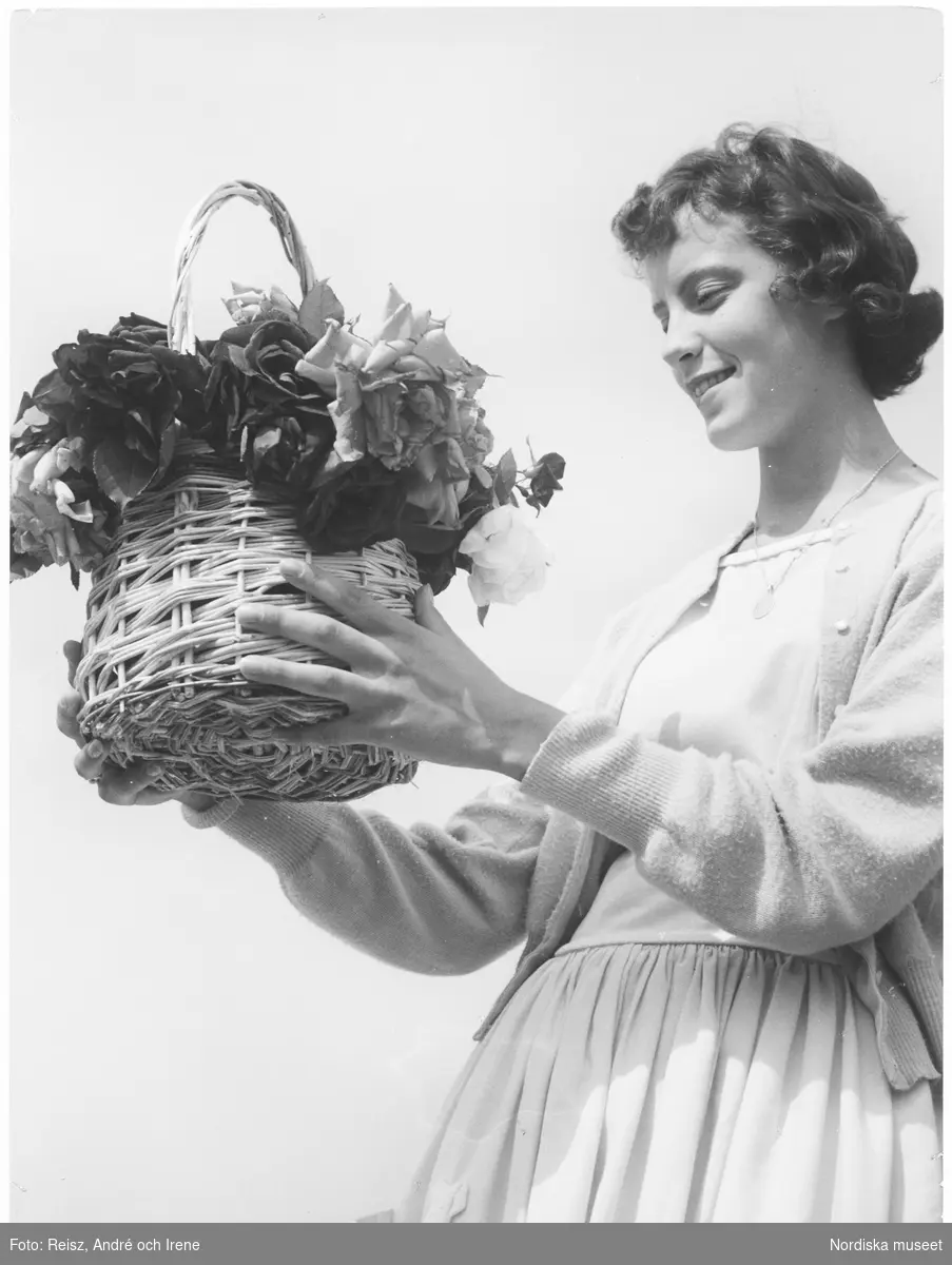 Porträtt av en kvinna med en korg full av rosor i händerrna.