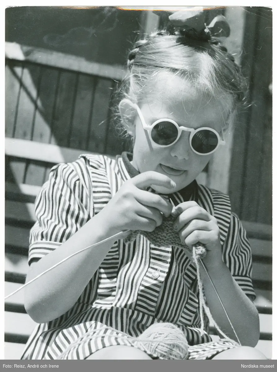 Porträtt av en flicka med solglasögon som stickar.