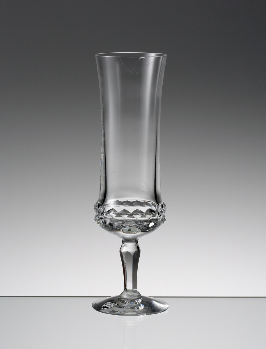 Design: Ingeborg Lundin.
Champagneglas. Närmast cylindrisk kupa med diamantslipad dekor runt kupans nedre del. Fasettslipat vulsterben.