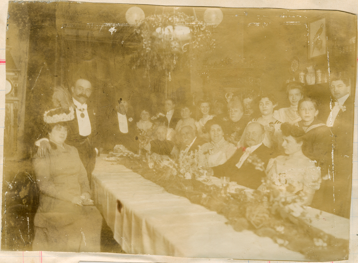 Motivet viser en ansamling ukjente mennesker rundt et festdekket bord. Blant menneskene i rommet kan en se Florentine Rostin og mor Sonja Rostin. Over bordet henger en lysekrone.