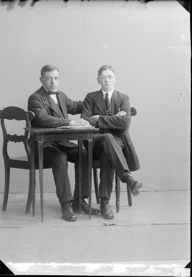 Två pojkar i tonåren sitter vid ett bord med en tidning.