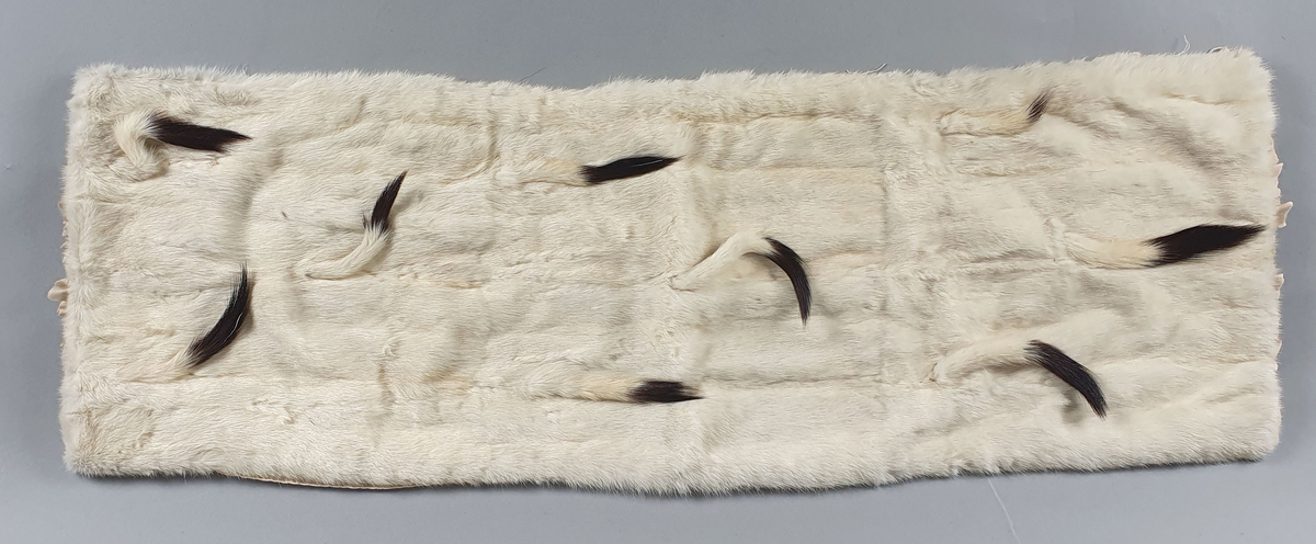 Krage og to mansjetter av røyskatt i vinterdrakt (hermelin) med haletupper. Noen av haletuppene er løse. Tydelige spor av at krage og mansjetter er klippet av et plagg.