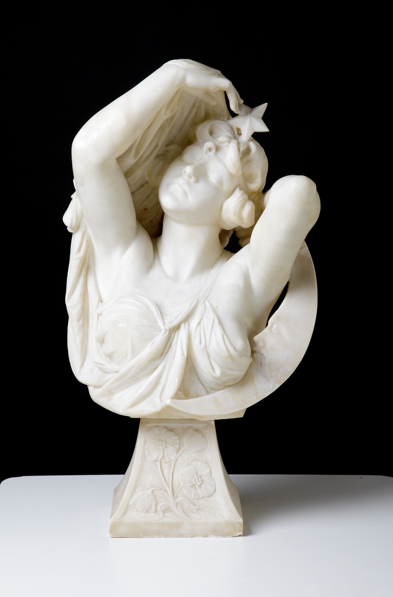 Byst av marmor, kallad "Nattens Drottning". 
Byst av sensuell kvinna med upplyftade armar. Till höger syns en månskära (med antytt ansikte) vid hennes arm och över huvudet syns en stjärna.
Står på sockel med blomdekor.