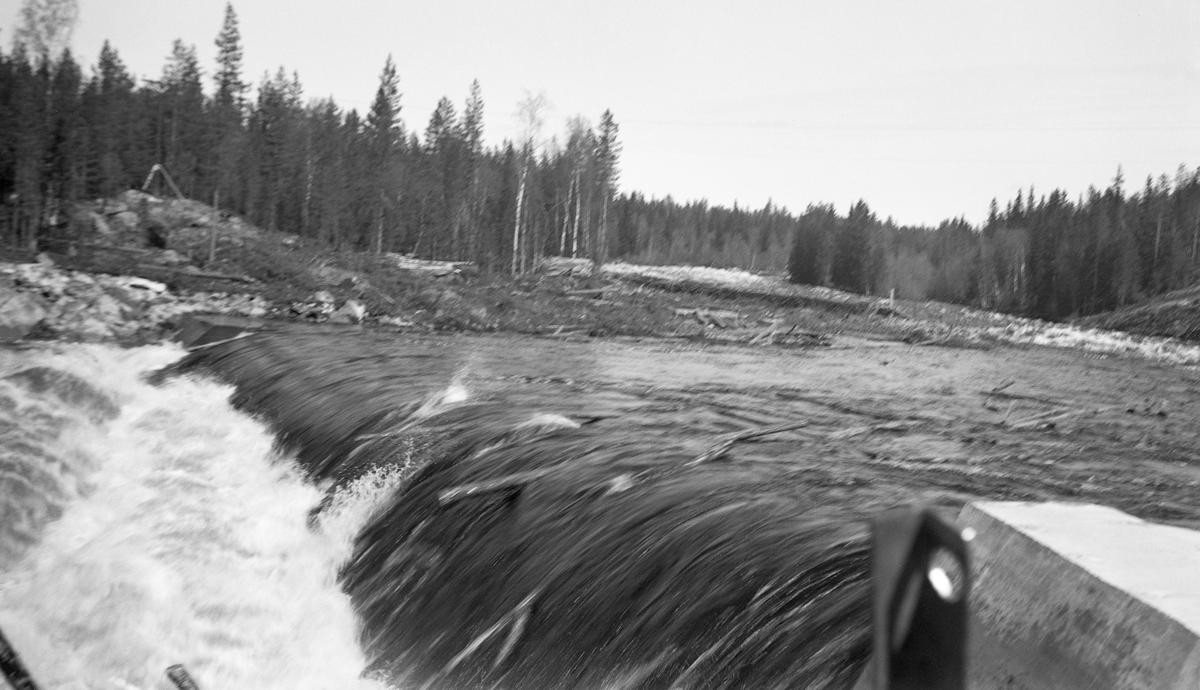 Tømmerfløting i elva Søndre Osa i Åmot kommune i Hedmark. Fotografiet er tatt våren 1936, ved den da nybygde kraftverksdammen ved Kvernfallet. I forgrunnen ser vi hvordan vannet og tømmerstokkene fløt over den avrundete damkrona. Den underliggende konstruksjonen, som vi ikke ser på dette bildet, var utført i armert betong. I 1936 var det innmeldt 383 088 tømmerstokker til fløting fra Osensjøen og tilflytende vassdrag. 28 prosent av stokkene ble levert ved Slemma, 10 prosent ved Nordre Osa, 7 prosent ved Brøa, 13 prosent ved Ena med Ulvsjøvassdraget, 7 prosent ved Tverrena og resten, 35 prosent, ble levert ved Osensjøens strender. Alt dette tømmeret. pluss noe av et kvantum på 72 506 stokker som var levert ved Søndre Osa, skulle passere den nye kraftverksdammen ved Kvernfallet. Aktørene i fløtinga var naturlig nok spente på om dammen kom til å bli et hinder der stokkene satte seg fast på eller like nedenfor dammen. Det skjedde ikke. Kvernfalldammen kom ikke til å skape nevneverdige problemer for tømmerfløtinga.