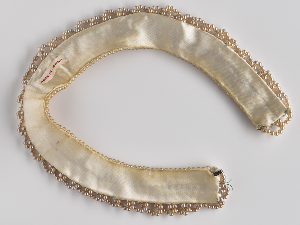 Perlekjede med tilhørende pappeske i beige farge og mønster som imiterer skinn. 

Diverse smykker som har tilhørt Synnøve Brændshøi. De fleste er nok fra 40- og 50-tallet.