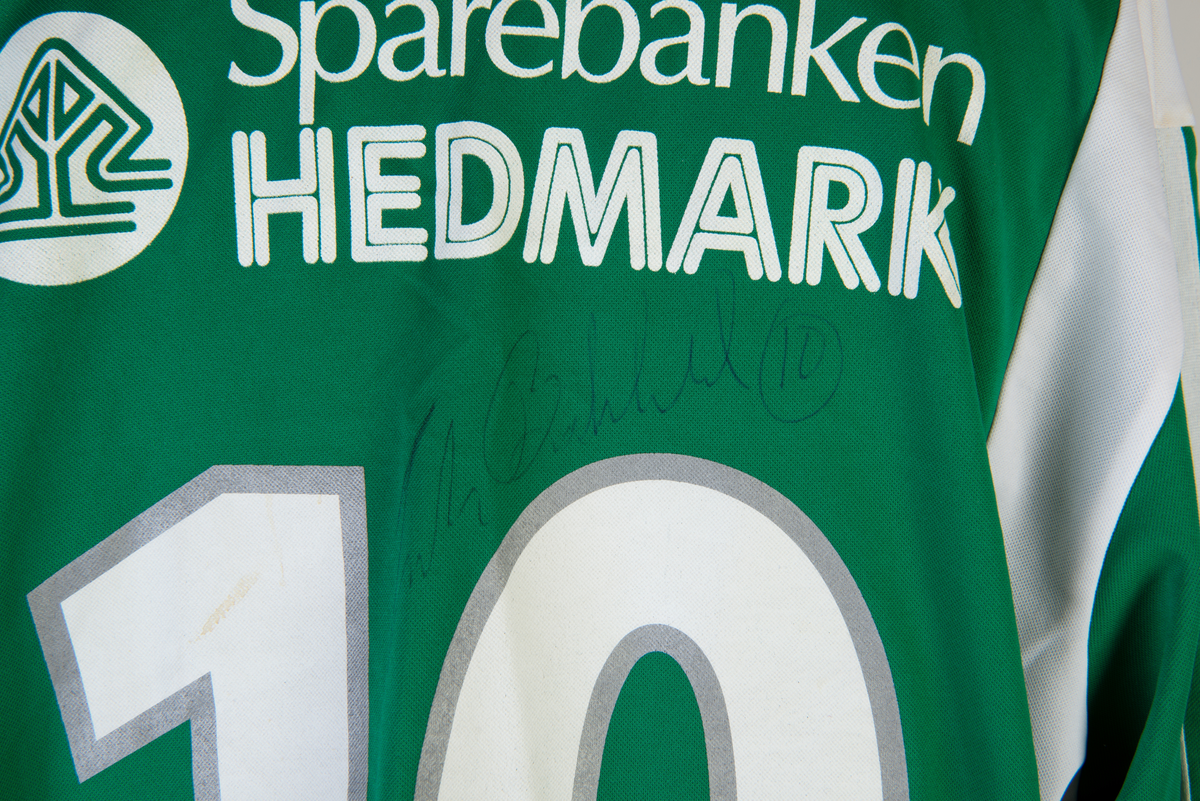 Langermet fotballtrøye nr. 10, Hamarkameratene, signert spiller Frode Birkeland. Ellers dekket av firmanavn/sponsorer. Hamkamfargene grønt og hvitt.