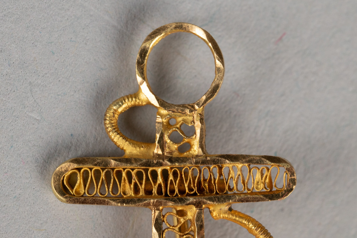 Nål i gullfiligrans, formet som et anker. Dekorert med monogram