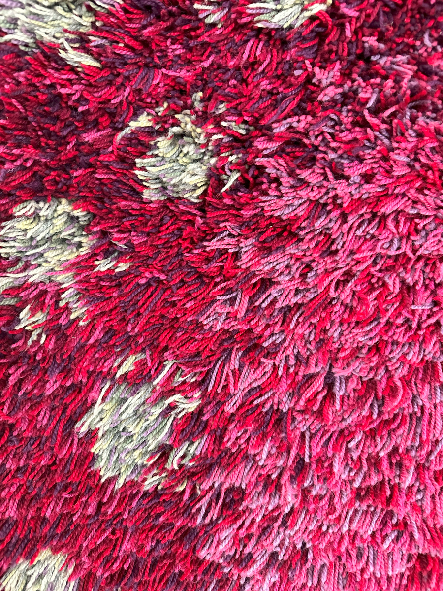 Vävd matta i ryateknik, bestående av oblekt lingarns varp och grått nöthårs inslag. Ryaknuten, 3-5cm lång, gjord av 3 trådar ryagarn, är knuten mellan 1,1cm nöthårs-inslag i grått och inramad av en 3cm röd kant på långsidorna. Kortsidorna har 4 lin-inslag samt 2 och 3cm bred röd nöthårskant i inslagsrips på respektive sidor. Kortsidorna har också drejad frans.