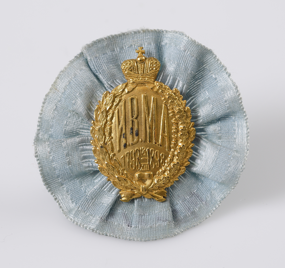 Kotiljong/brosch i ljusblått siden och pressat emblem i gul metall med text; "HBMA 1798 18/XII 1898", under rysk kejserlig krona.

Inskrivet i huvudbok 1969.