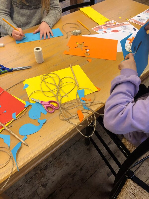 Barn sitter og lager flotte papirhvaler i ulike farger