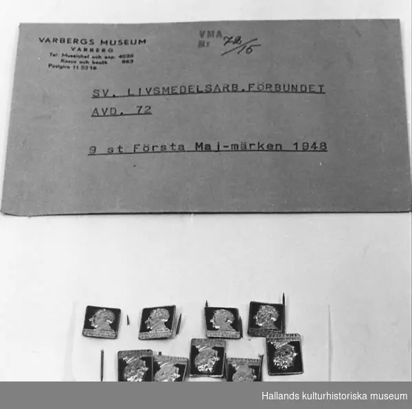 " styck Första-Majmärken. I rött och guld. Profil av man, text?: "Gunnar Andersson 1 maj 1948". Höjd= 1,9 cm. Bredd= 1,5 cm. 