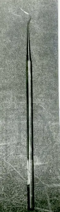 Riflet, kantet skaft.
Instrumentet består av en rund rett stang, bøyer svakt bakover 2,8 cm og skrått frem igjen 1,3 cm.
Ved festet til stangen er diam. 0,15 cm, gradivis tynnere og ender i en spiss.
